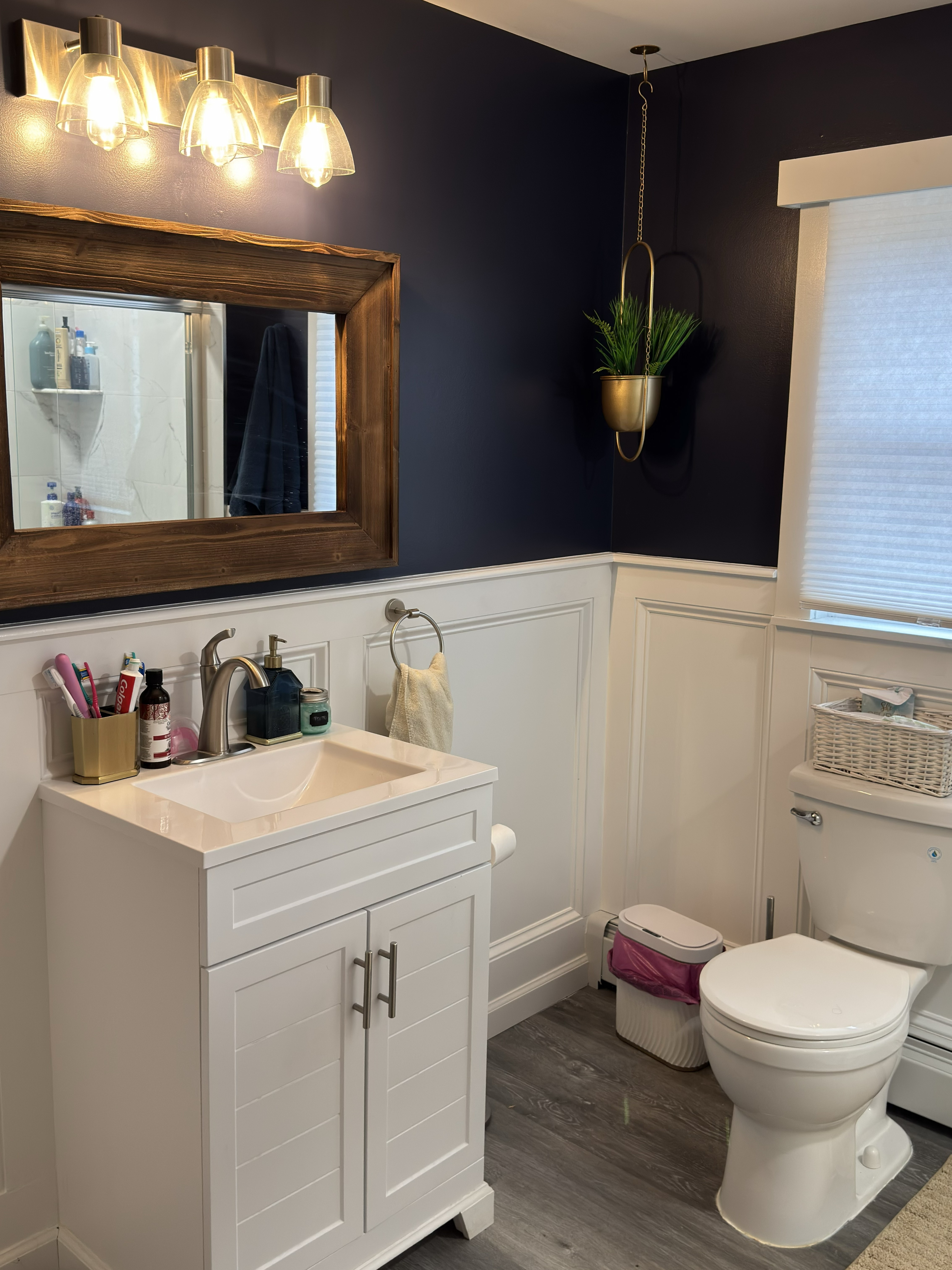 Bathroom with white panel wainscoting, blue upper walls, and gray plank flooring